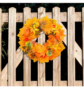 Detailed view of autumn wreath with maple leaves and pumpkins on wooden fence