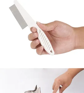 Detail of a ergonomic white pet flea comb held by hand with fine steel needles