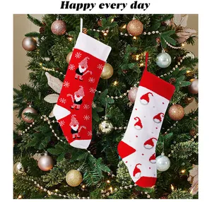 Detail view of red and white knitted Christmas stockings hanging on a festive tree
