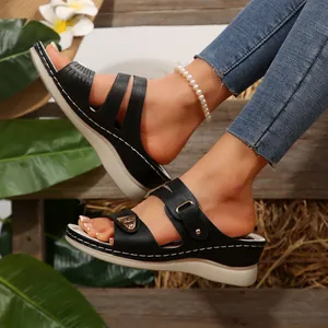 Close-up of black platform wedge sandals with intricate carved detailing and white stitching