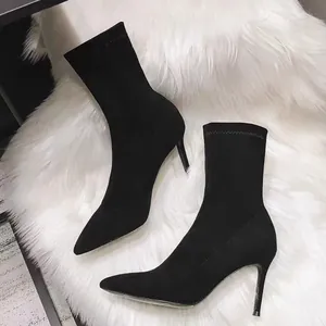 Detailansicht eleganter schwarzer Wildleder-Stiefeletten mit spitzer Kappe auf weißem Fell