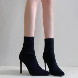 Elegante schwarze Stretch-Stiefeletten aus Wildleder mit Stiletto-Absatz an den Beinen.