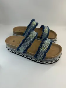 Detailansicht von Plateausandalen mit glitzernden Strasssteinen und blauen Fransenriemen