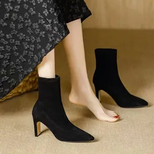 Seitenansicht eleganter schwarzer Wildleder-Stiefeletten mit Blumenrock kombiniert.
