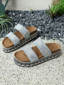 Plateausandalen aus Denim mit Strasssteinen und Jutesohle in einem sommerlichen Garten