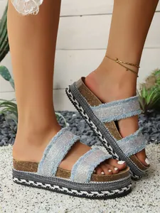 Detailansicht von sommerlichen Plateau-Sandalen aus Denim mit Strassriemen und Fransen