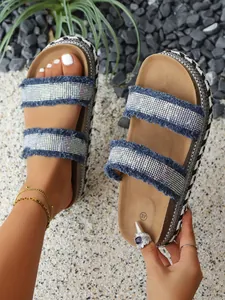 Nahaufnahme von Plateausandalen mit glitzernden Strasssteinen und Fransen-Denim-Riemen und Websohle