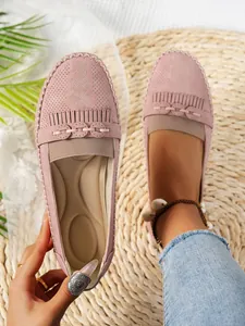 Gros plan de mocassins roses pour femmes avec découpes laser et détails de franges