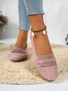 Gros plan détaillé des mocassins en daim rose pour femmes avec détails franges.
