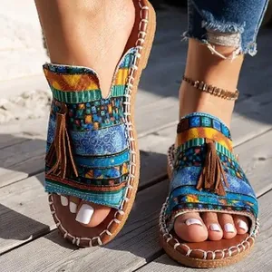 Close-up of bohemian flat slippers featuring colorful mosaic patterns and brown tassels