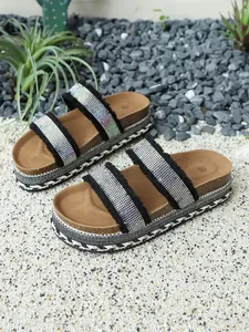 Detailansicht der Plateausandalen mit funkelnden Strassriemen und Fransenrändern.