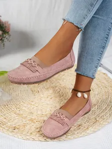 Mocassins en daim rose avec franges portés avec un jean bleu sur un tapis