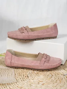 Détail de mocassins en daim rose pour femmes avec franges et nœud sur tapis tressé