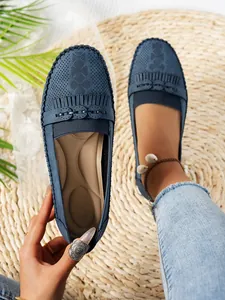 Gros plan de mocassins bleus perforés avec détails de franges sur un tapis de paille