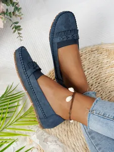 Détail des mocassins bleus pour femmes avec franges sur un tapis de paille.