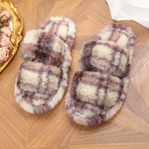 Primer plano de pantuflas de felpa a cuadros morados y crema sobre el suelo