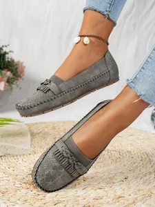 Vue détaillée de mocassins plats gris pour femmes avec glands et texture ajourée au laser.