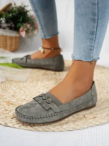 Gros plan sur des mocassins plats gris pour femmes avec franges et boucle en métal