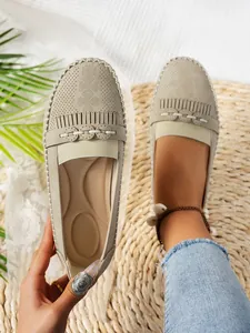 Vue détaillée de mocassins perforés beiges pour femmes avec design à enfiler et franges.