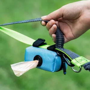 Close-up view of a blue dog waste bag dispenser attached to a neon green leash outdoors
