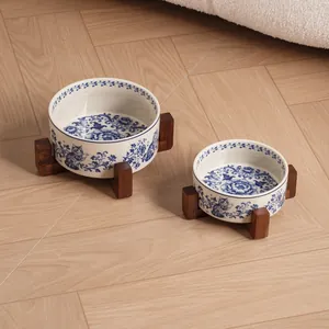 Vintage blue and white floral ceramic pet bowls with acacia wood stands on wood floor