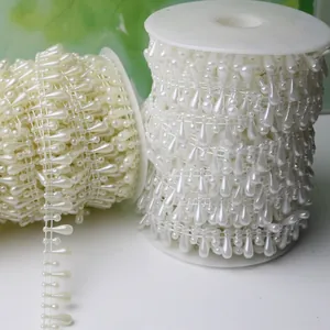 Vue détaillée de garnitures élégantes de perles blanches en forme de larme sur bobines.