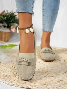 Gros plan détaillé de mocassins beiges pour femmes avec franges sur tapis de paille