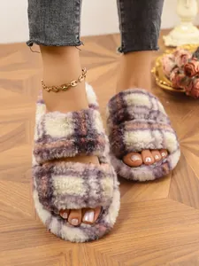 Detalle de cerca de zapatillas de felpa a cuadros con dos correas para mujer en casa