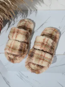 Detalle de cómodas pantuflas de felpa a cuadros con correas dobles para el hogar en invierno