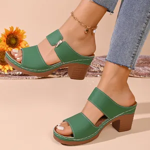Vue latérale de mules vertes à talons épais avec des détails de surpiqûres blanches.