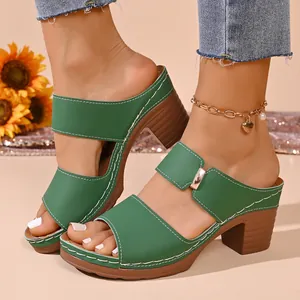 Vue de profil de mules à talons épais vert élégantes avec surpiqûres blanches.