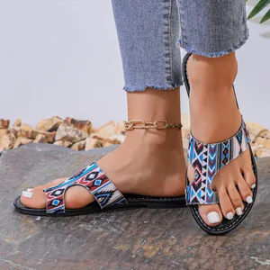 Dichtbij van dames sandalen met etnisch geometrisch patroon en teenlus.