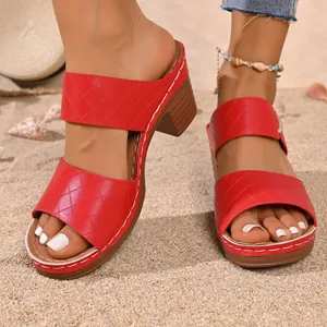 Mules à talons hauts matelassées rouges pour femmes sur une plage de sable ensoleillée