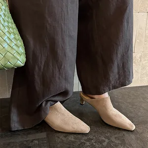 Mules élégantes en daim beige à bout pointu avec talons hauts portées par un mannequin