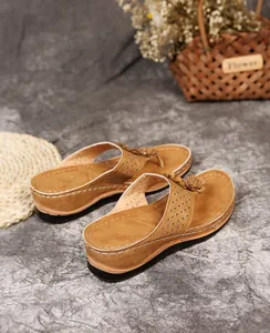 Detailansicht braune Damen-Keilsandalen mit Blumenakzenten und Ziernähten am Rand.