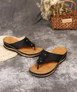 Detailansicht schwarzer Keil-Zehentrenner-Sandalen mit Blumenakzenten und weißen Nähten