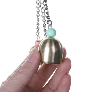 Detailed view of durable brass alloy bell bird toy held by hand for cage accessory