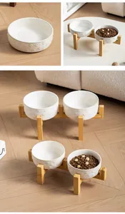 Detalle de cuenco de cerámica blanca con relieve de huella de gato y soporte de madera bambú