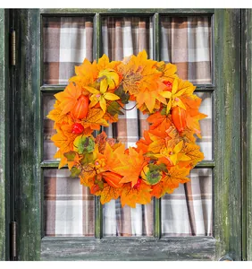 Detailed view of an autumn wreath with orange maple leaves and mini pumpkins on a door