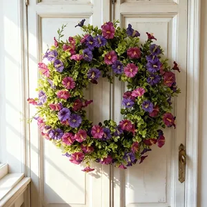 Detalle de corona de flores artificiales moradas y rosas en una puerta blanca vintage