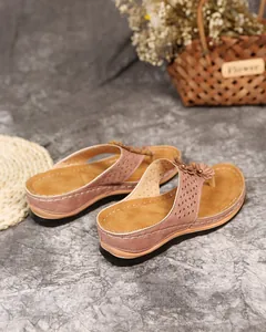 Detailansicht von rosa Keil-Flip-Flop-Sandalen mit eleganten Blumenakzenten und Nähten.