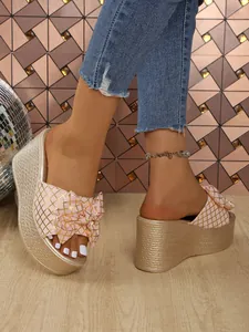 Close-up view of pink bow wedge sandals featuring gold grid and platform soles