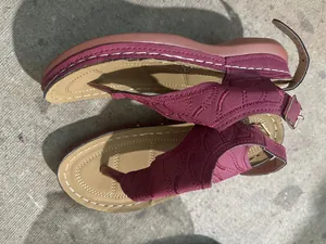 Detailweergave van bordeauxrode Romeinse sandalen met golfpatroon en verstelbare gesp