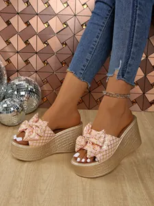 Detailed view of pink bowknot wedge platform sandals with gold grid pattern and woven sole