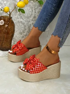 Detailed view of red wedge platform sandals with gold grid and bow tie detail