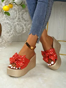 Close-up of stylish red bow wedge sandals with gold grid pattern and high platform heel
