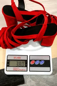 Nahaufnahme der roten Riemchen-Sandalen mit Blockabsatz auf einer digitalen Waage