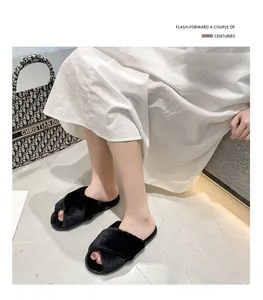 Gros plan de chaussons en fausse fourrure noire à brides croisées avec robe blanche