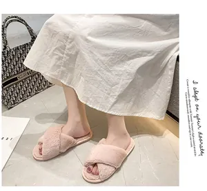 Gros plan de chaussons en fausse fourrure rose à bandes croisées sur sol en marbre