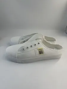 Mules blancas de lona sin cordones con bordes deshilachados.